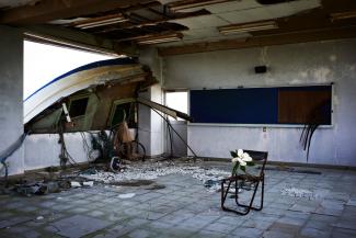Flower on a chair in an empty room, a wrecked boat resting in the window
